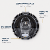 Top-down view of a clear food-grade insulated tumbler lid with callout labels explaining features: clear lid that is easy to see and clean, easy-to-use slider opens and closes smoothly, spill-resistant design helps reduce spills and sip or use a straw compatibility designed for either, on a light gray background.
